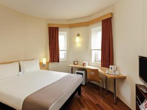 a hotel room with a large bed and a desk at Ibis Eskisehir in Eskisehir +93 photos