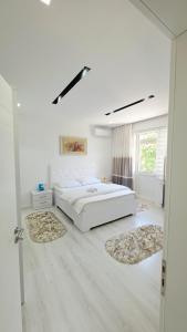 a white bedroom with a large bed and two rugs at Selimi House in Shirokë
