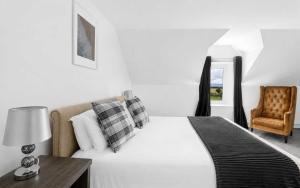a bedroom with a white bed and a chair at Dunallan Farm Cottage with Optional Hot Tub & Stunning Views in Island of Bute