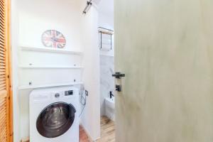 a washing machine in a bathroom with a clock on the wall at Charming Open Space in Costa Smeralda in Olbia