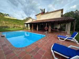a swimming pool with two chairs and a house at Finca Panaca Jaguey 7 in Quimbaya