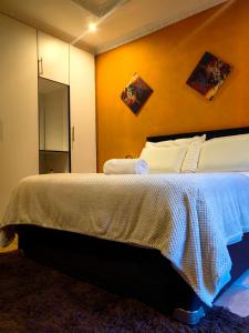 a bedroom with a large bed with a yellow wall at Mukani B&B in Lobatse