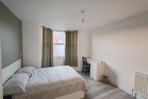 a bedroom with a bed and a desk and a window at Jurassic Coast Gateway Exmouth Escape in Exmouth