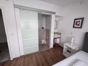 a bedroom with a sliding glass door leading to a bathroom at Gästehaus Am Rebenhang in Mehring