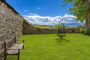 a bench sitting in a yard next to a stone wall at Dunallan Farm Cottage with Optional Hot Tub & Stunning Views in Island of Bute