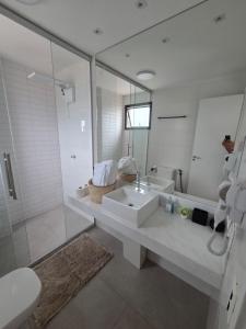 a white bathroom with a sink and a mirror at Apartamento espaçoso de luxo in Goiânia