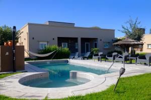 a swimming pool with a hammock next to a house at Vi Hosting Cabañas in Salta