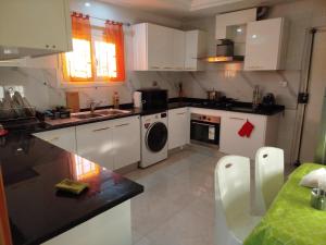 a kitchen with white cabinets and a washer and dryer at Tawfik in Midoun +5 photos