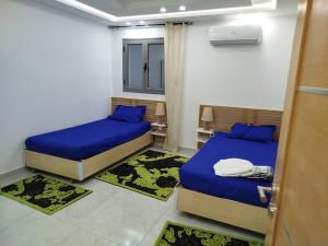 two beds in a small room with blue sheets at Tawfik in Midoun
