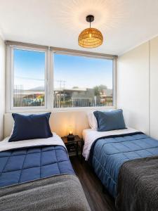 two beds in a room with a large window at Departamento Villarrica Vista al Volcán y Piscina in Villarrica +21 photos