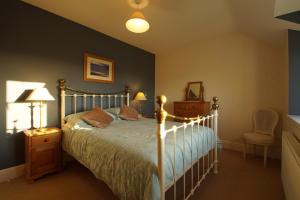 a bedroom with a bed and a chair at Hendy Iago in Aberdaron