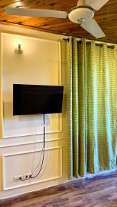 a flat screen tv on a wall next to a curtain at Umda Hotel in Nathia Gali