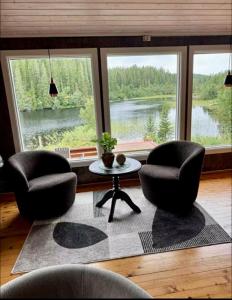 a living room with two chairs and a table and windows at Lakeside cabin in Snofugl +8 photos