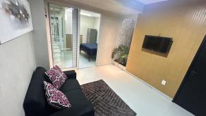 a living room with a black couch and a tv at Mini apê de luxo montese in Fortaleza