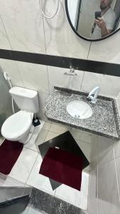 a bathroom with a toilet and a sink and a mirror at Mini apê de luxo montese in Fortaleza