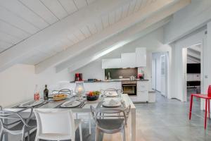 a white kitchen and dining room with a table and chairs at Loft & Jacuzzi - Happy Rentals in Riva del Garda