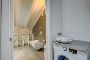 a bathroom with a toilet and a washer and dryer at Loft & Jacuzzi - Happy Rentals in Riva del Garda