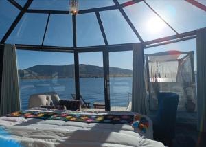 a bedroom with a large glass window with a bed at Titicaca wasy lodge in Puno