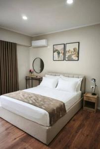 a bedroom with a large white bed and two mirrors at Velia Rooms in Përmet