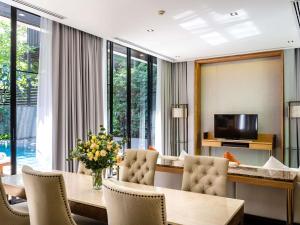 a dining room with a table and chairs and a television at V Villas Hua Hin - MGallery Collection in Hua Hin