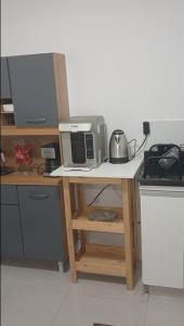 a kitchen with a table with a microwave and a stove at COLOFT - Studio Térreo com Acessibilidade in Anápolis