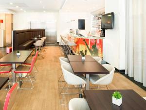a restaurant with tables and chairs and a tv at ibis Esch Belval in Esch-sur-Alzette