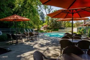 an outdoor patio with tables and chairs and umbrellas at The Jack London Lodge in Glen Ellen