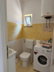 a bathroom with a toilet and a washing machine at Apartman Ilaria in Medulin +8 photos