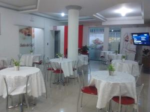 un salón de banquetes con mesas y sillas blancas en Hotel Dal Gobo, en Ponta Grossa
