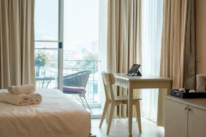 a hotel room with a bed and a desk and a balcony at Shamrock Hotel Pattaya in Pattaya South
