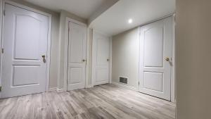an empty room with white doors and wooden floors at House - Bungalow in Hamilton