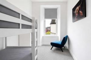 a bedroom with a bunk bed and a blue chair at The Fountain View Apartment in Rothesay