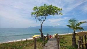 a wooden pathway leading to a beach with umbrellas at Pousada Tia Cleide in Caraguatatuba