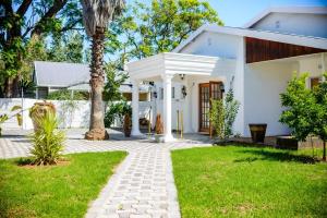 a white house with a tree in the yard at Makay's Guests House in Kimberley