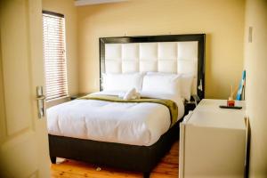a bedroom with a large bed with a large headboard at Makay's Guests House in Kimberley
