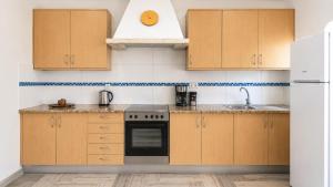 a kitchen with wooden cabinets and a stove top oven at Tonel Apartments in Sagres