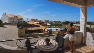 a woman standing on a balcony looking at a pool at Tonel Apartments in Sagres