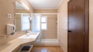 a bathroom with a sink and a shower and a mirror at Tonel Apartments in Sagres