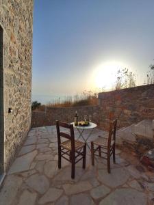a table and chairs on a stone patio with the sunset at Ελαιόλιθοι Μάνη Villas in Oitylo +11 photos