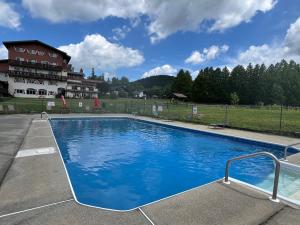 a large blue swimming pool in front of a building at Mittersill Alpine Resort in Franconia +13 photos