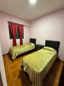 two beds in a room with red curtains at Fortunata Urban in San Miguel de Tucumán
