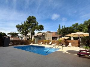 a swimming pool with two chairs and an umbrella at Suite Pinamar 09 in Pinamar