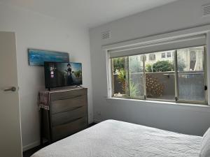 a bedroom with a bed and a television and a window at Beachfront Apartment in Melbourne