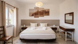 a bedroom with a bed and a desk and a window at Tonel Apartments in Sagres