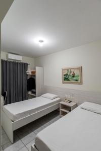 a hotel room with two beds and a table at Romas Hotel in Umuarama