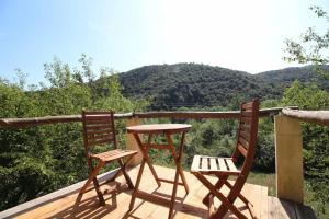 two chairs and a table on a deck with mountains at CAMPING Pleine Nature in Boule - dÊ¼Amont