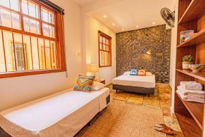 a bedroom with two beds and a stone wall at Wafeh Guest House - Fleming - Bar & Jardim in Belo Horizonte