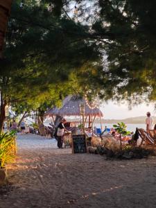 a group of people on a beach with a shack at Andi's Bungalow in Gili Islands