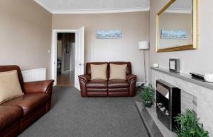 a living room with two leather chairs and a fireplace at Lady Mary Sea View in Rothesay +9 photos