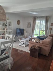 a living room with a couch and a tv at Maison ensoleillée plage a pied in Houlgate